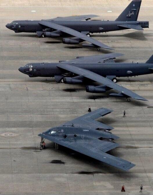 Three military aircraft, two B-52 bombers and one B-2 stealth bomber, parked on an airfield.