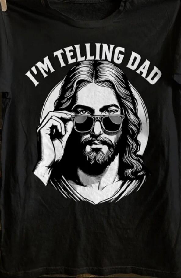 I'M TELLING DAD. A stylized depiction of Jesus Christ wearing sunglasses, adjusting them with one hand, printed on a black t-shirt.