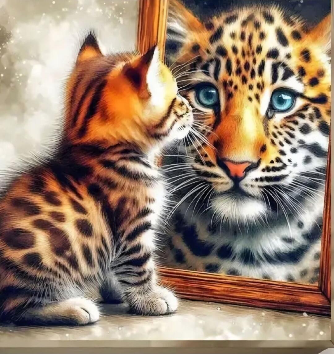 A small kitten is looking into a mirror at its reflection, which resembles a tiger.