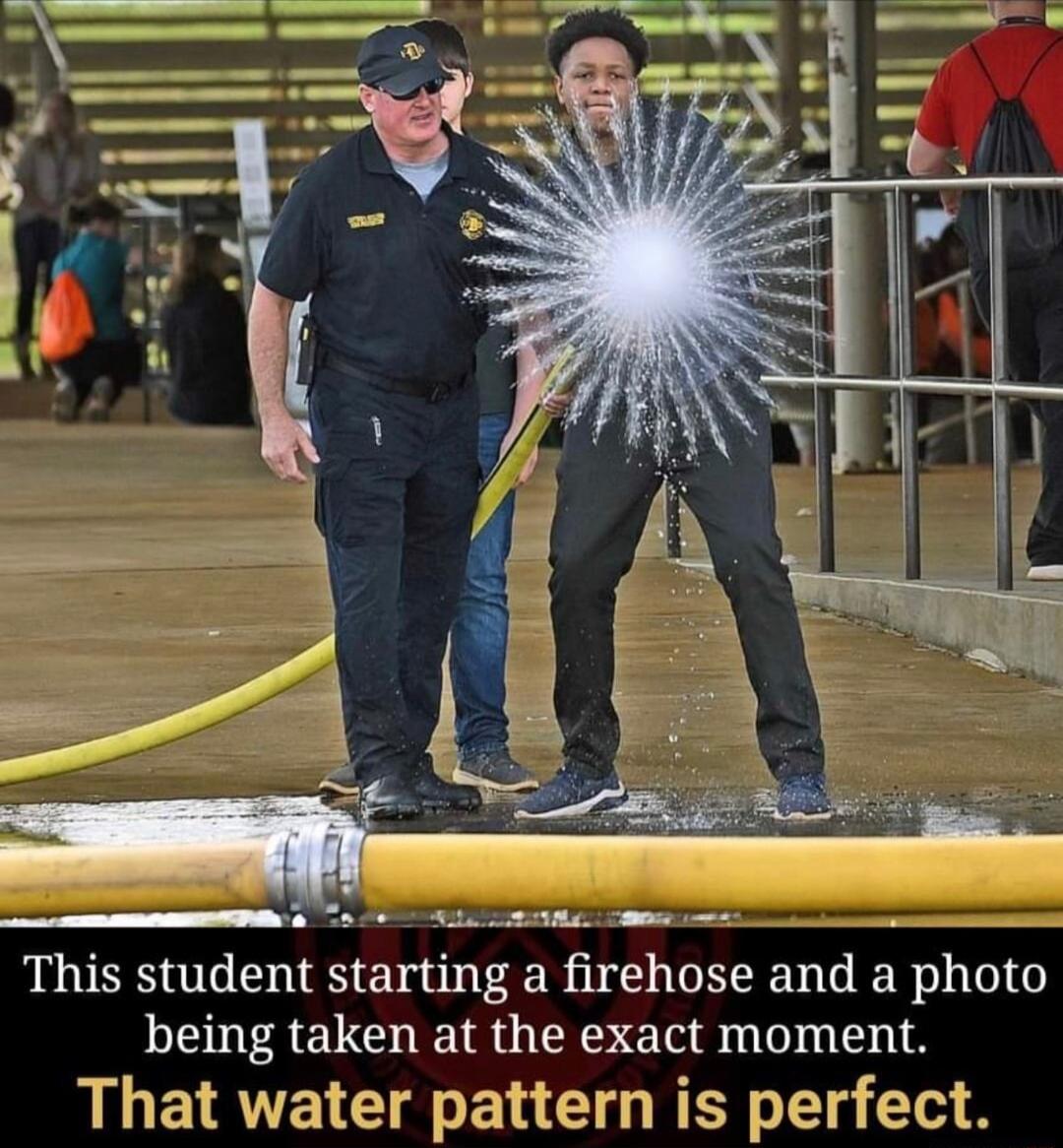 2T i s e _ This student starting a firehose and a photo being taken at the exact moment That water pattern is perfect