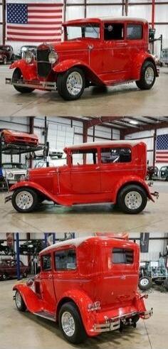 A bright red vintage car displayed indoors with an American flag in the background.