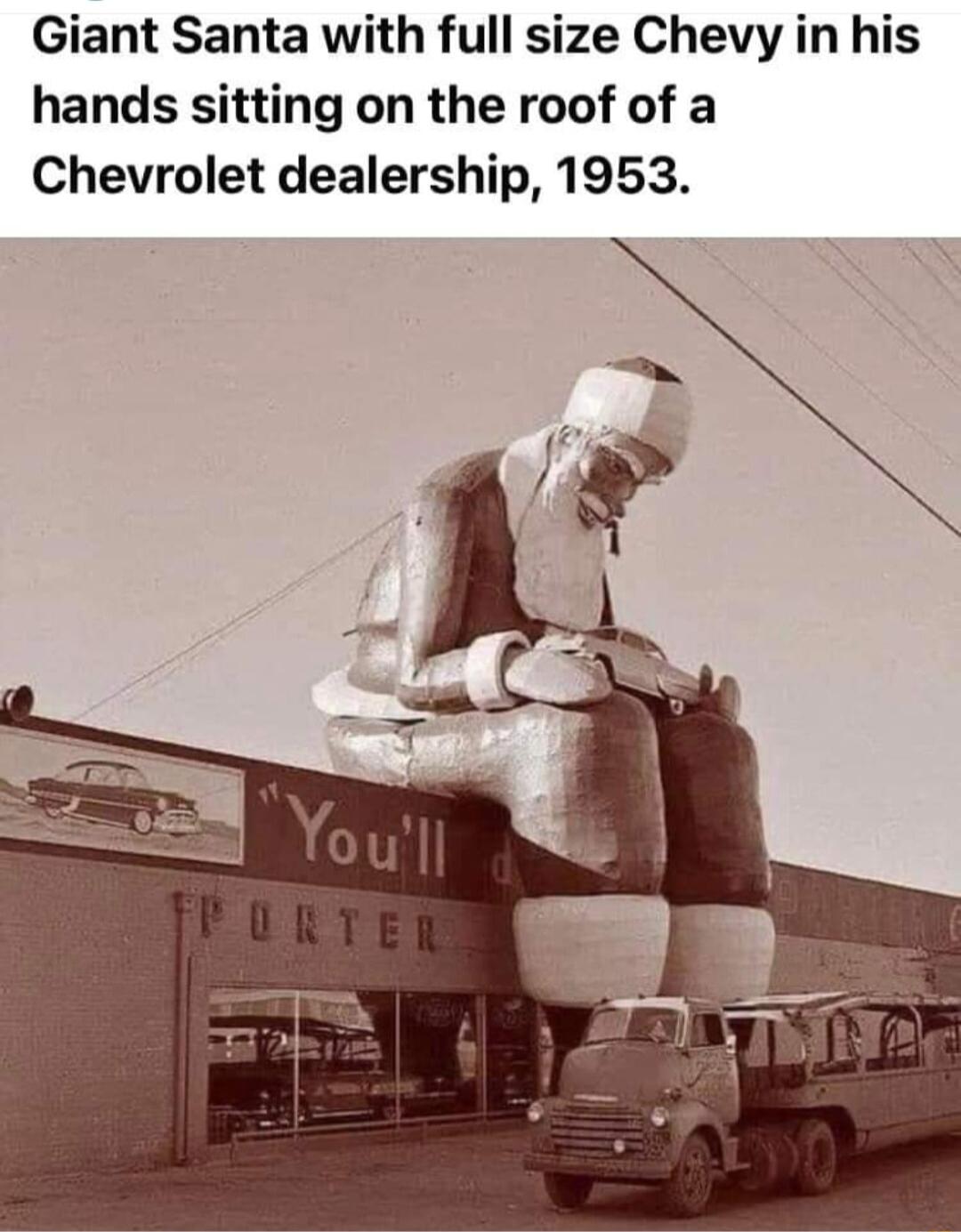 Giant Santa with full size Chevy in his hands sitting on the roof of a Chevrolet dealership 1953