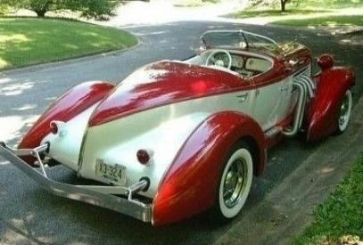 Vintage red and white convertible car parked on a driveway.