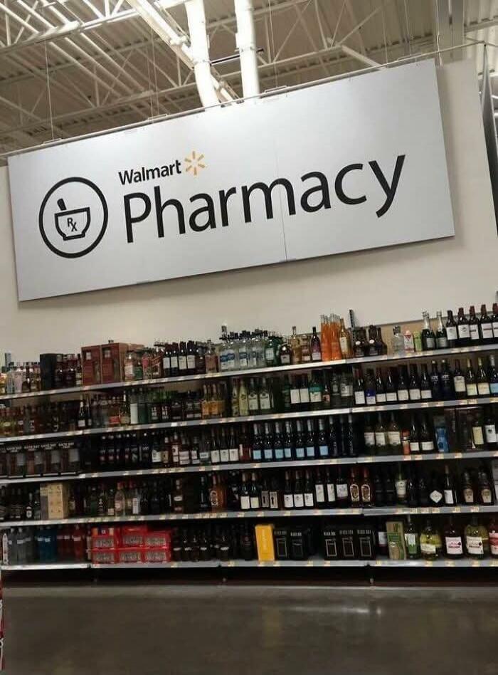 A 'Walmart Pharmacy' sign with a mortar and pestle icon is displayed above multiple shelves fully stocked with various alcoholic beverages, including wine, spirits, and beer.