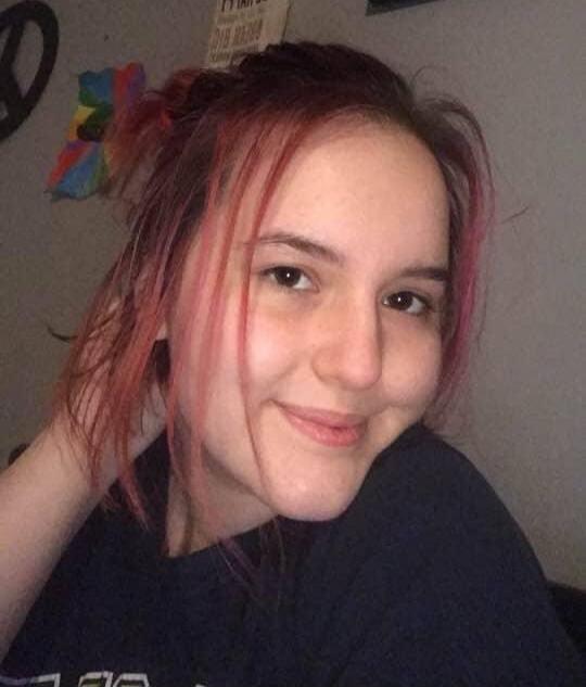 A young person with pink-dyed hair smiling at the camera.