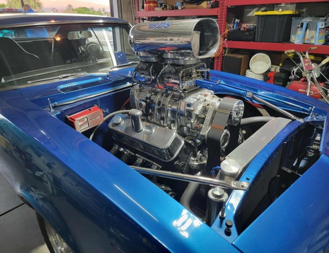 Blue classic car with a prominent supercharger in the engine bay.