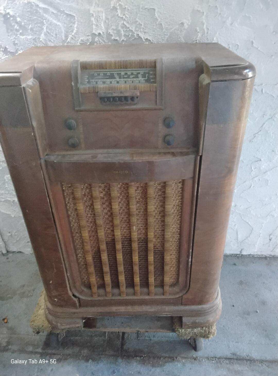 An old wooden radio with a tuning dial and a woven speaker grille. The brand 'PHILCO' is faintly visible on the grille.