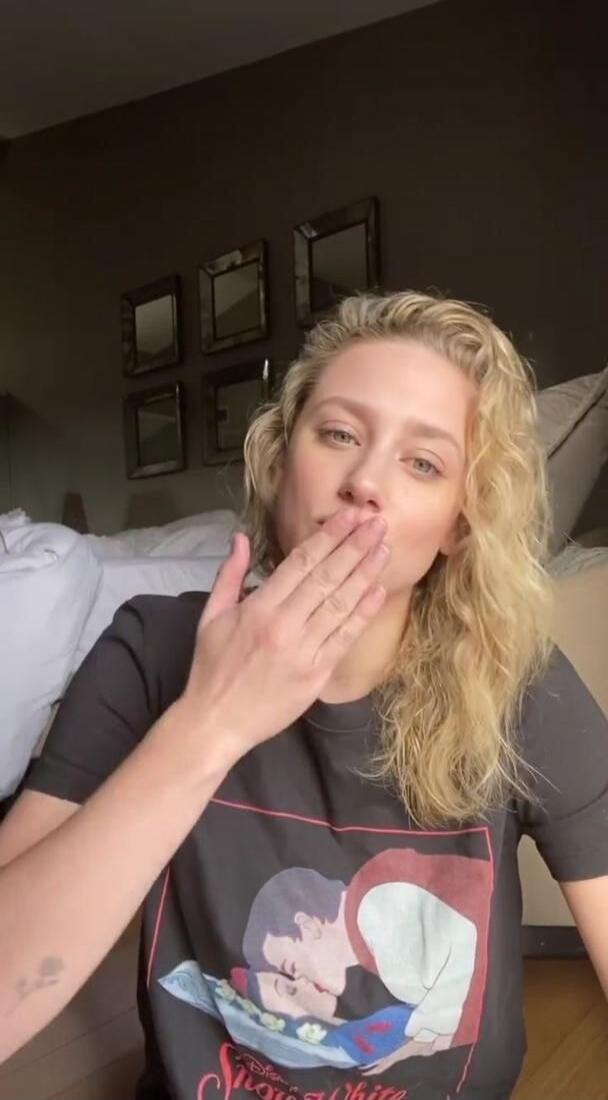 A woman blowing a kiss. She is wearing a t-shirt with 'Snow White' printed on it.