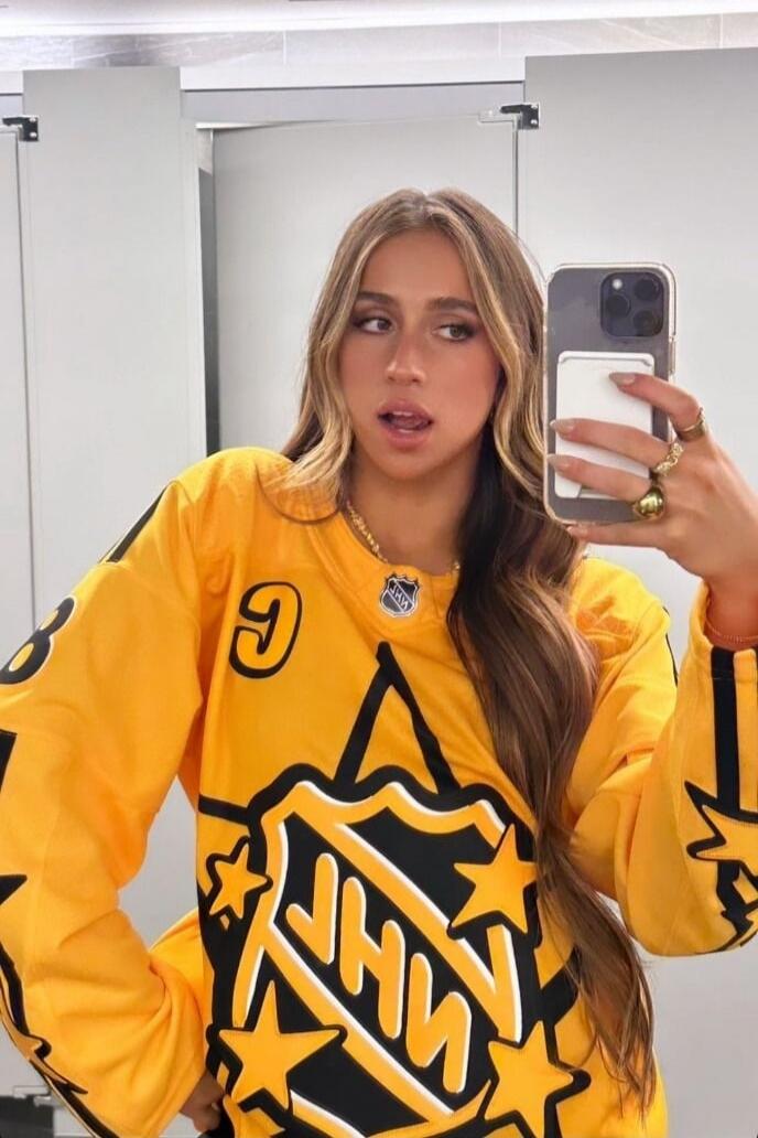 NHL logo on a bright yellow hockey jersey; a woman taking a mirror selfie in a restroom or dressing area.