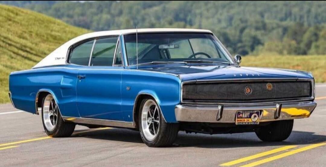 A classic blue and white Dodge Charger car is parked on a road.