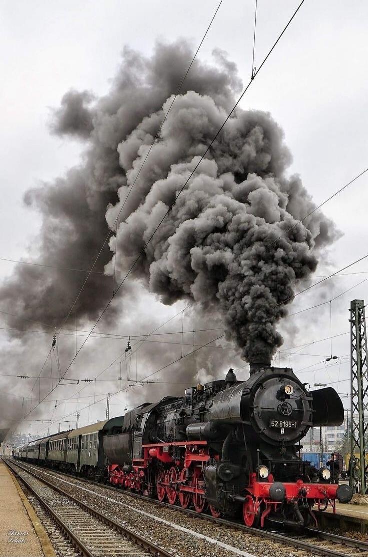 A steam locomotive is emitting a large amount of black smoke.