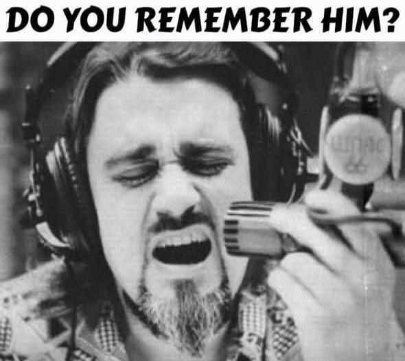 DO YOU REMEMBER HIM? A man with a beard and headphones singing into a microphone.