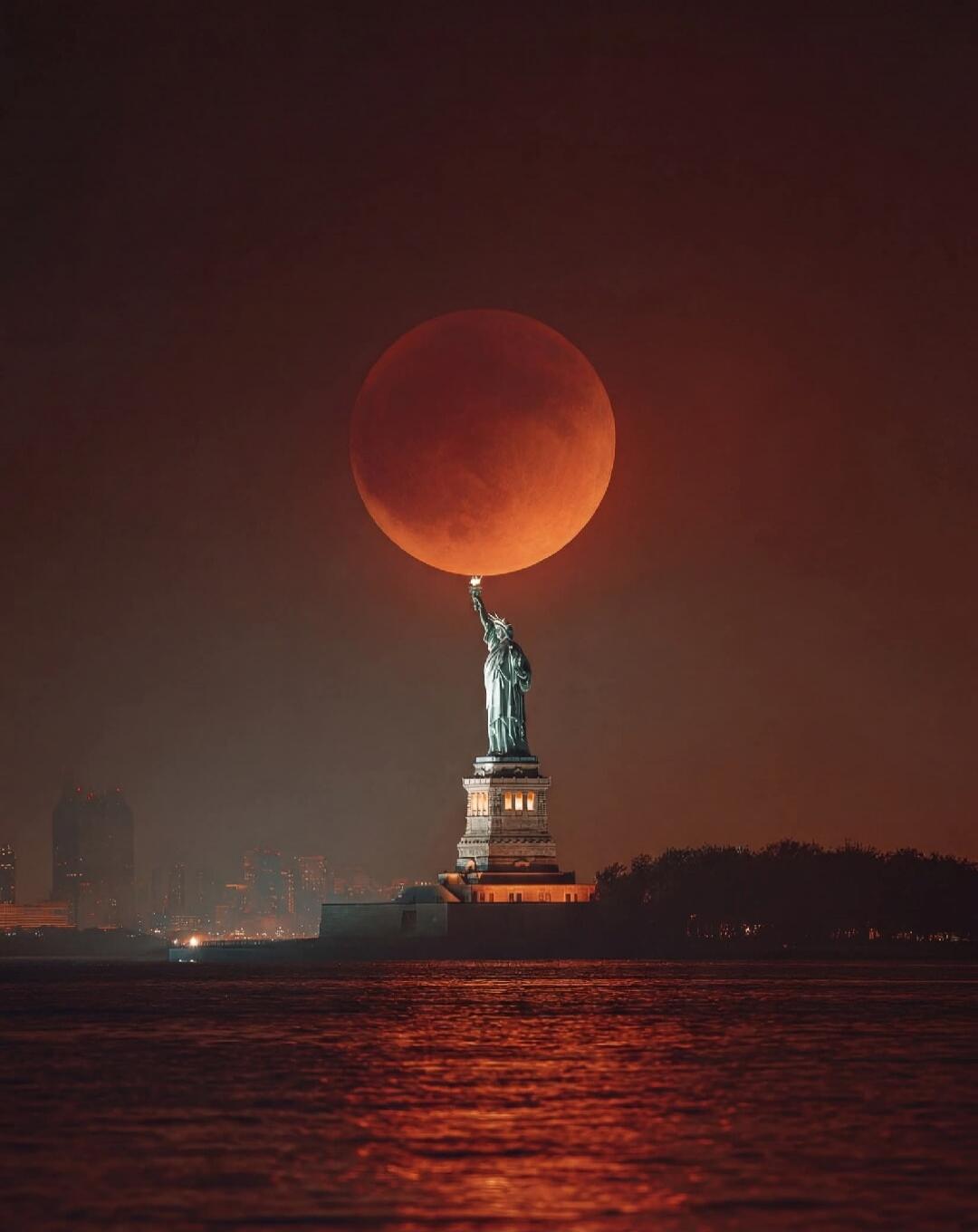 The Statue of Liberty holding the moon during a lunar eclipse.