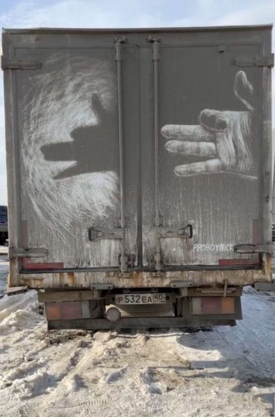 На задних дверях фуры нарисованы мелом две руки: левая тень и правая рука, будто они касаются друг друга.