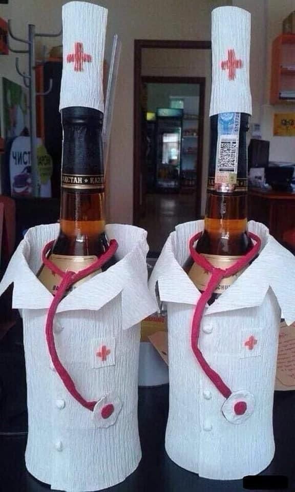Две бутылки одеты как врачи: белые халаты, шапочки с красным крестом и стетоскопы, обвисшие вокруг горлышка.