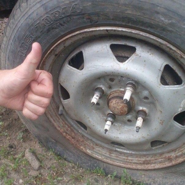 Большой палец вверх рядом с колесом; на диске видны торчащие шпильки, ржавчина на ступице и ободе.