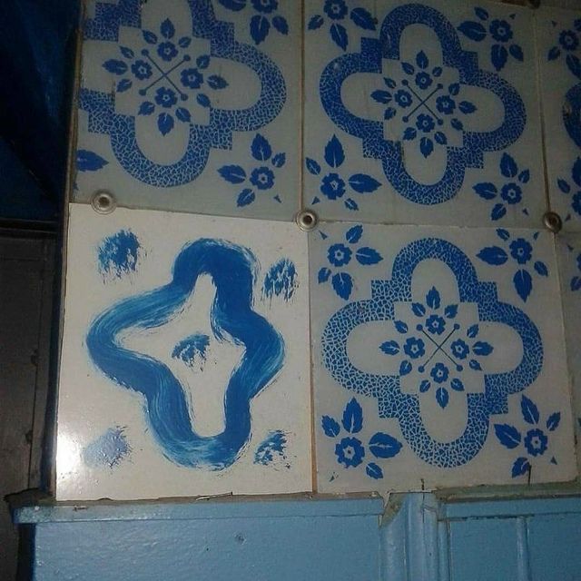На плитке изображены синие узоры: повторяющийся цветочный мотив, а на одной плитке рукотворная синяя фигура в абстрактной форме.