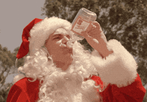Santa Claus drinking from a bottle outdoors.