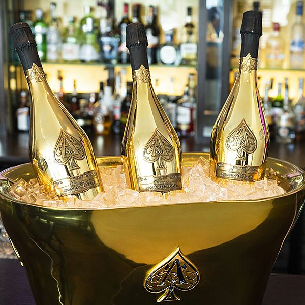 Three champagne bottles chilling in an ice-filled gold bucket.