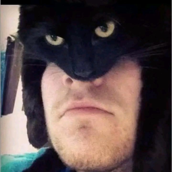 A man wearing a black cat hat with yellow eyes, making a pout.
