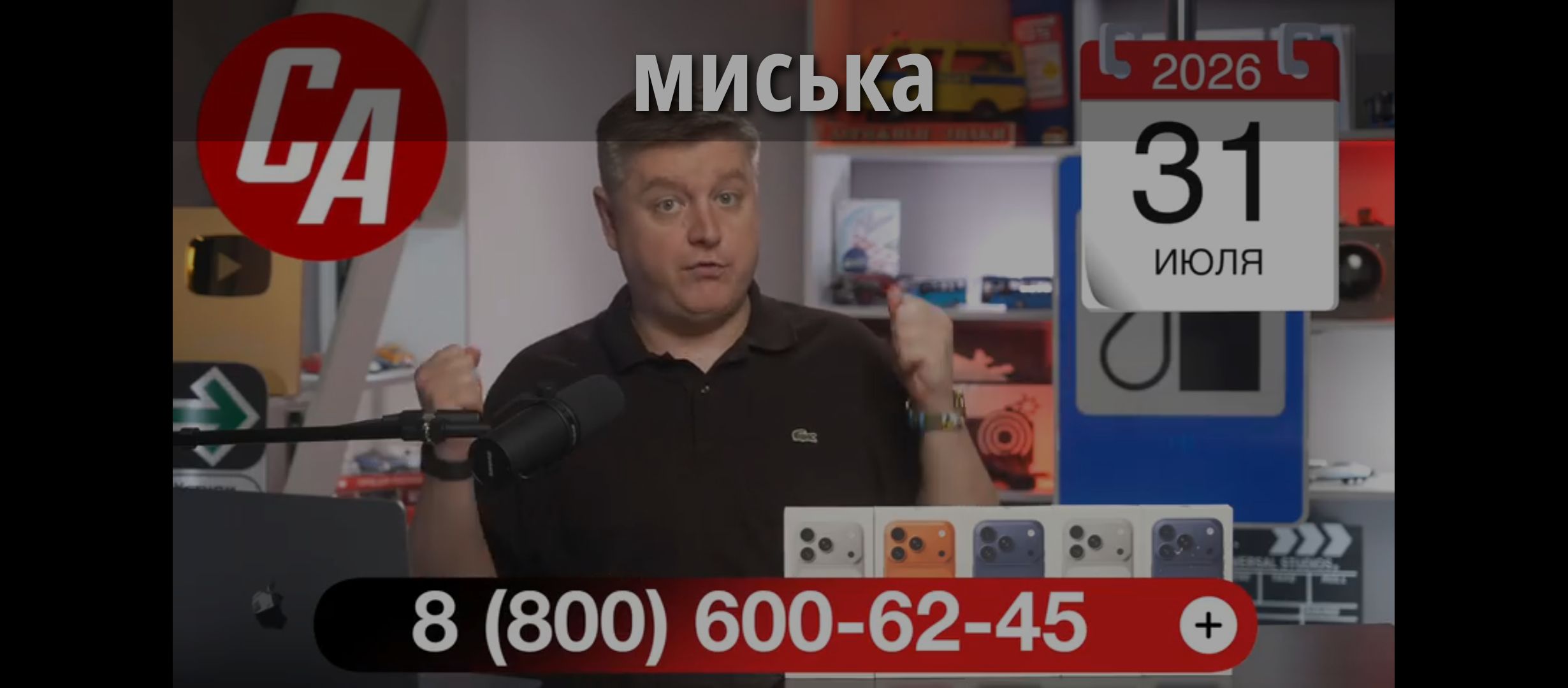МИСЬКА. CA. 2026. 31 ИЮЛЯ. 8 (800) 600-62-45. UNIVERSAL STUDIOS. Мужчина в студии, вероятно, ведет презентацию или обзор новых моделей телефонов, которые стоят перед ним.