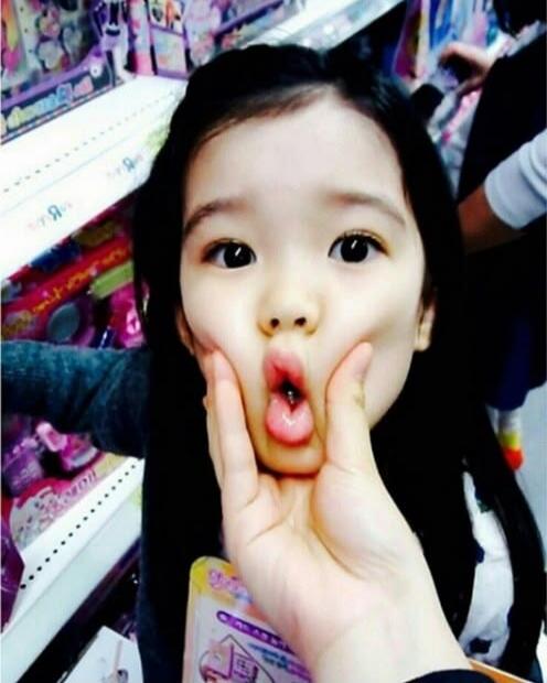 A child's face being playfully squeezed, making a funny expression.