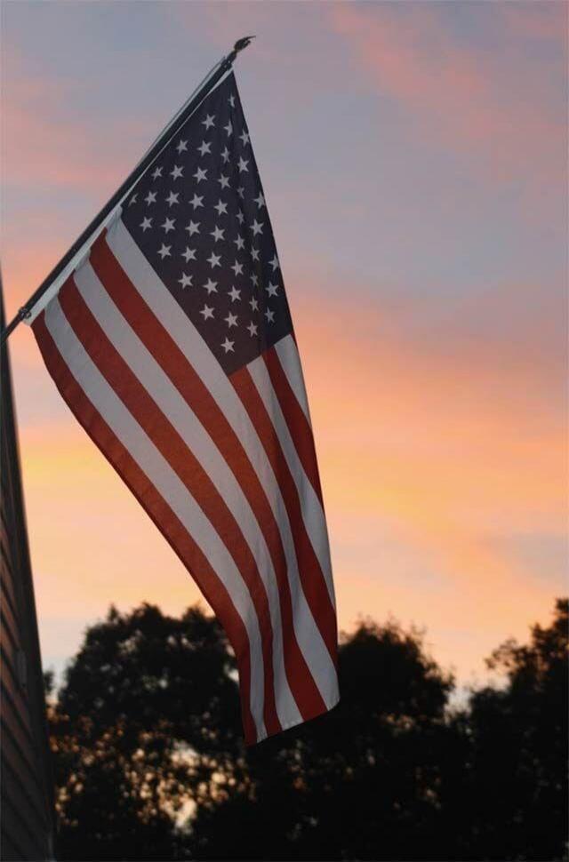 The American flag is waving against a sunset sky.