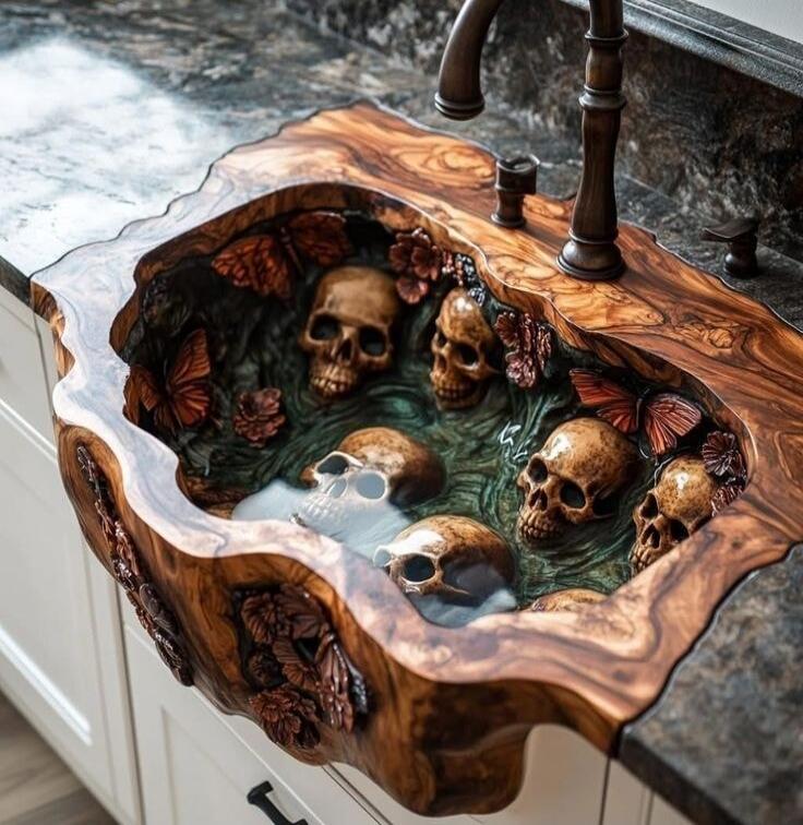 Artistic carved wooden sink with skulls and flowers filled with water.