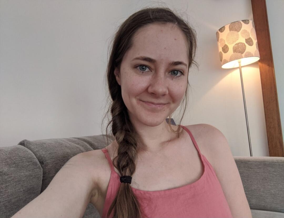 A young woman taking a selfie on a couch indoors.