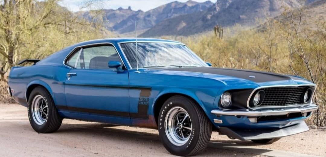 Blue classic muscle car parked on a desert road.