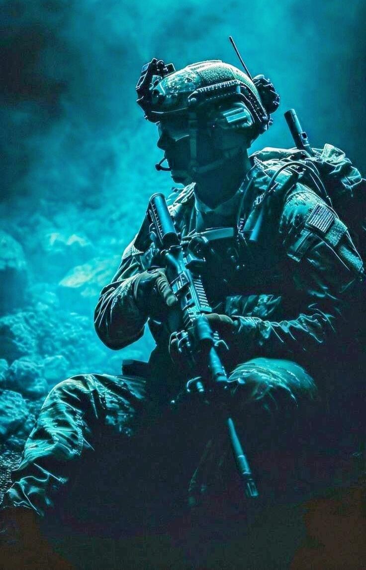 A soldier in full combat gear crouching with a rifle in a smoky blue-lit environment.
