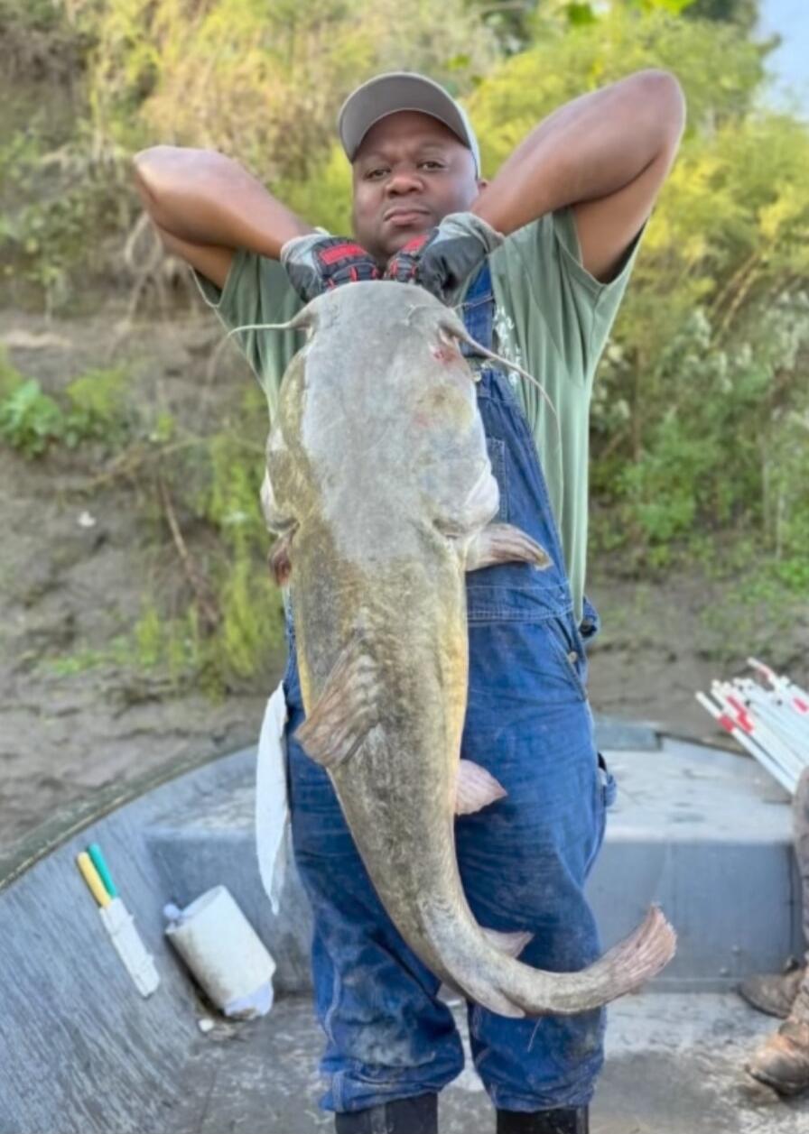 Man on a boat holding a large fish.