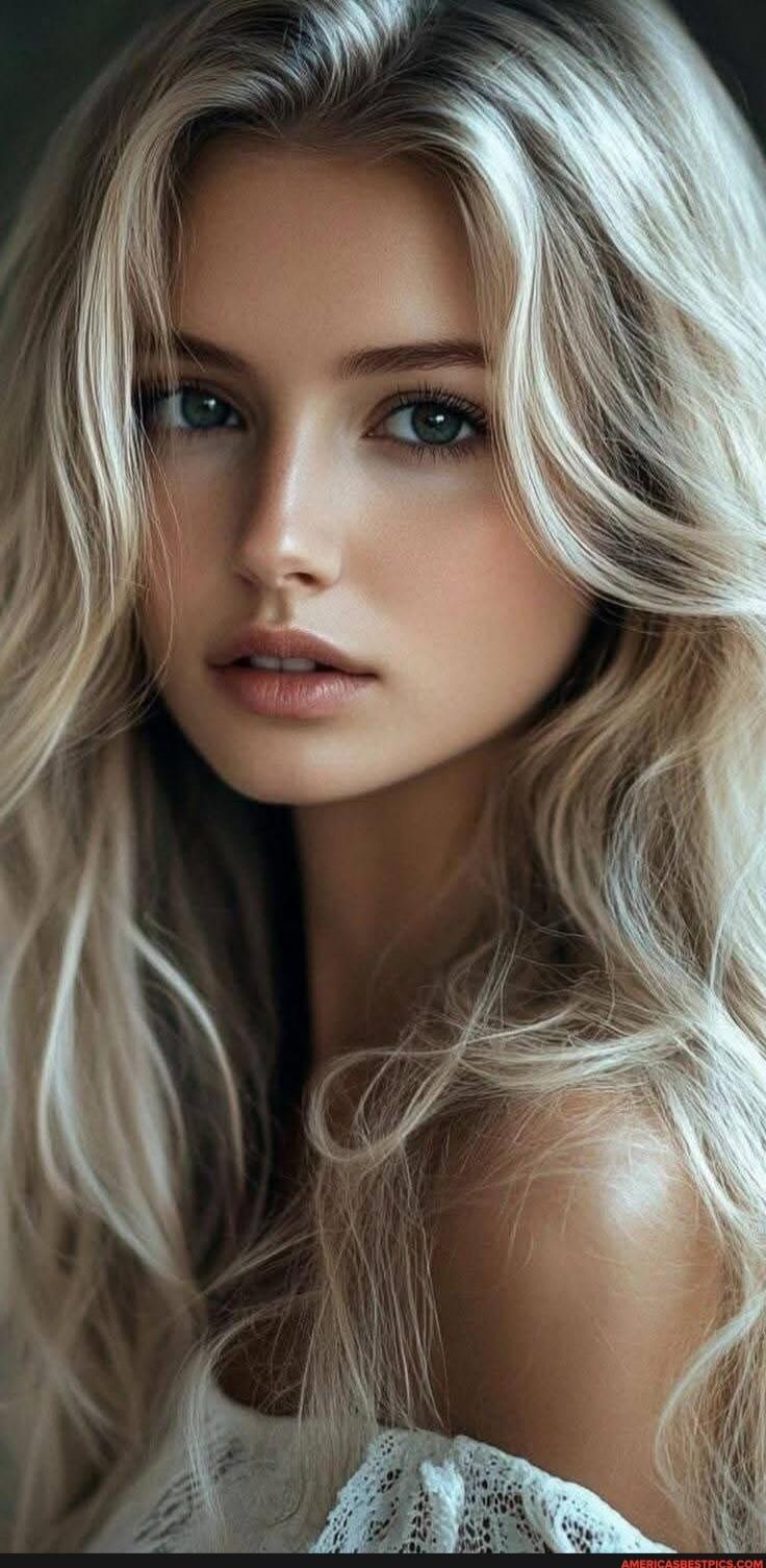 Portrait photo of a young woman with long blonde hair and blue eyes, wearing a white lace top.