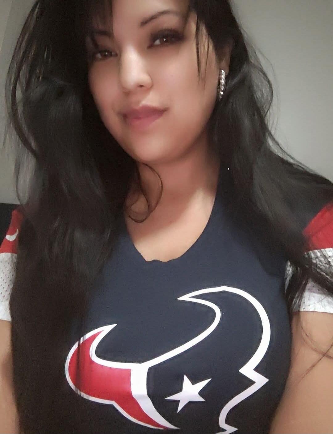 A woman taking a selfie wearing a navy t-shirt with red and white sleeves and a large white star logo.