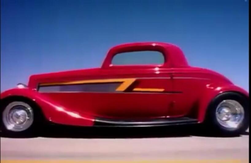A red vintage hot rod car with a yellow stripe along the side.