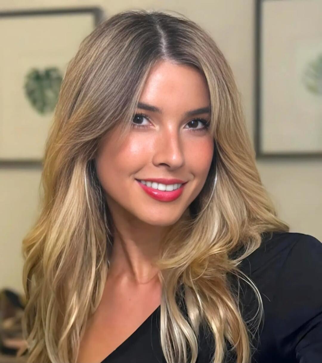 A smiling woman with blonde hair wearing a black top.