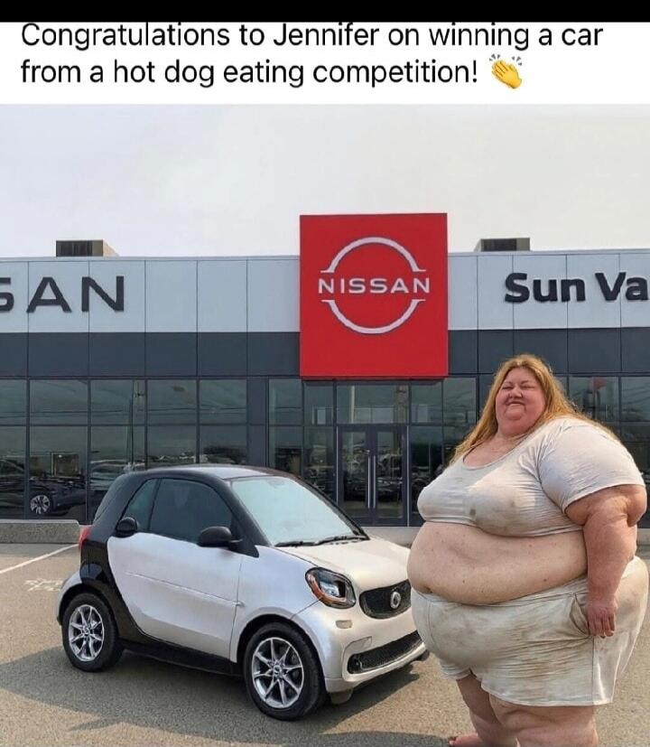 Congratulations to Jennifer on winning a car from a hot dog eating competition! A very obese woman stands next to a small Smart car in front of a Nissan dealership.