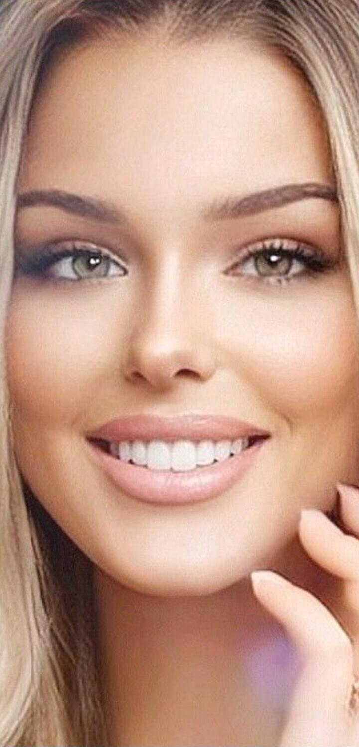 A close-up portrait of a smiling woman with light makeup.