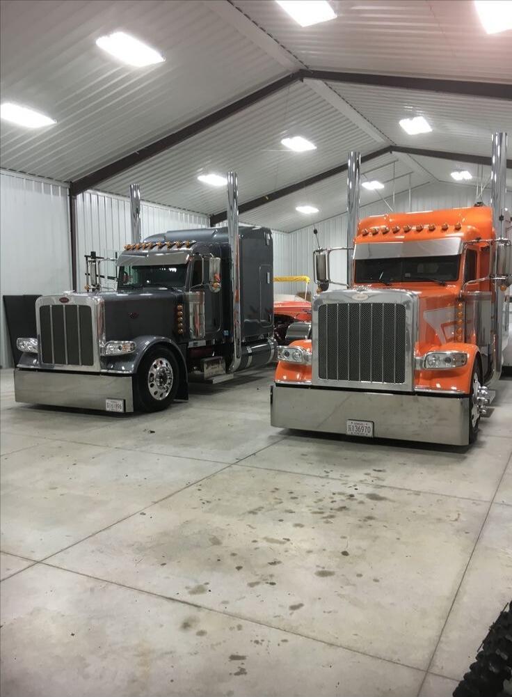 Two large semi-trucks parked inside a warehouse-style garage.