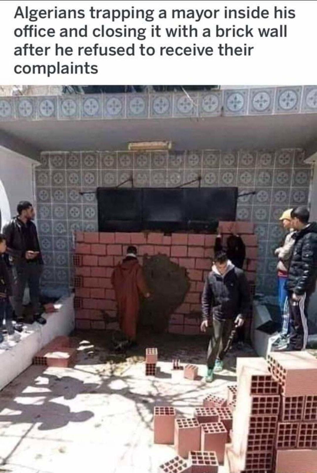 Algerians trapping a mayor inside his office and closing it with a brick wall after he refused to receive their complaints