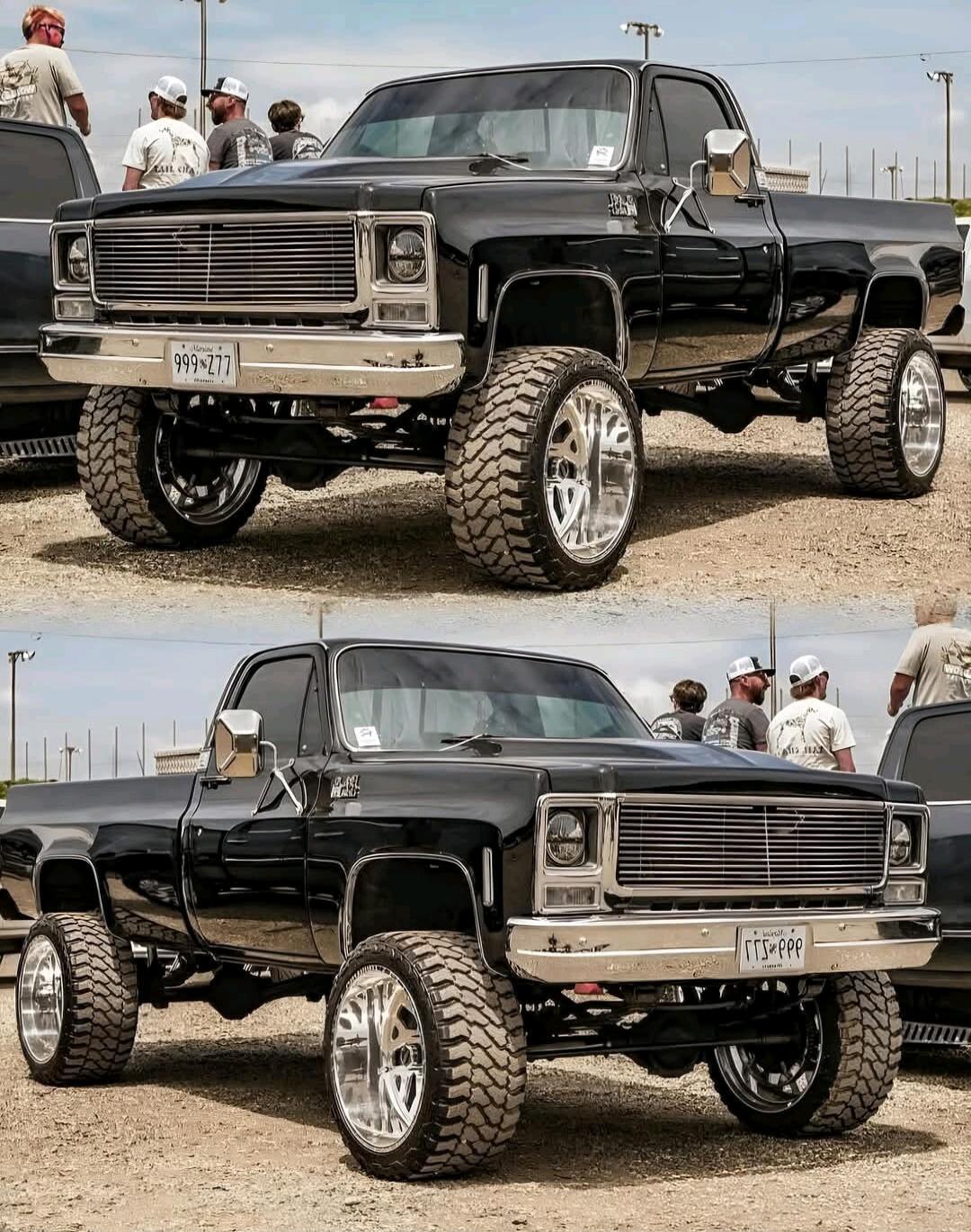 Black lifted vintage pickup truck with oversized tires at a car show.