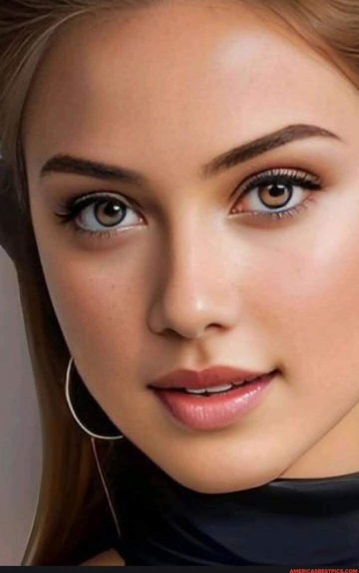 Close-up portrait of a young woman with makeup, wearing hoop earrings and a black top.