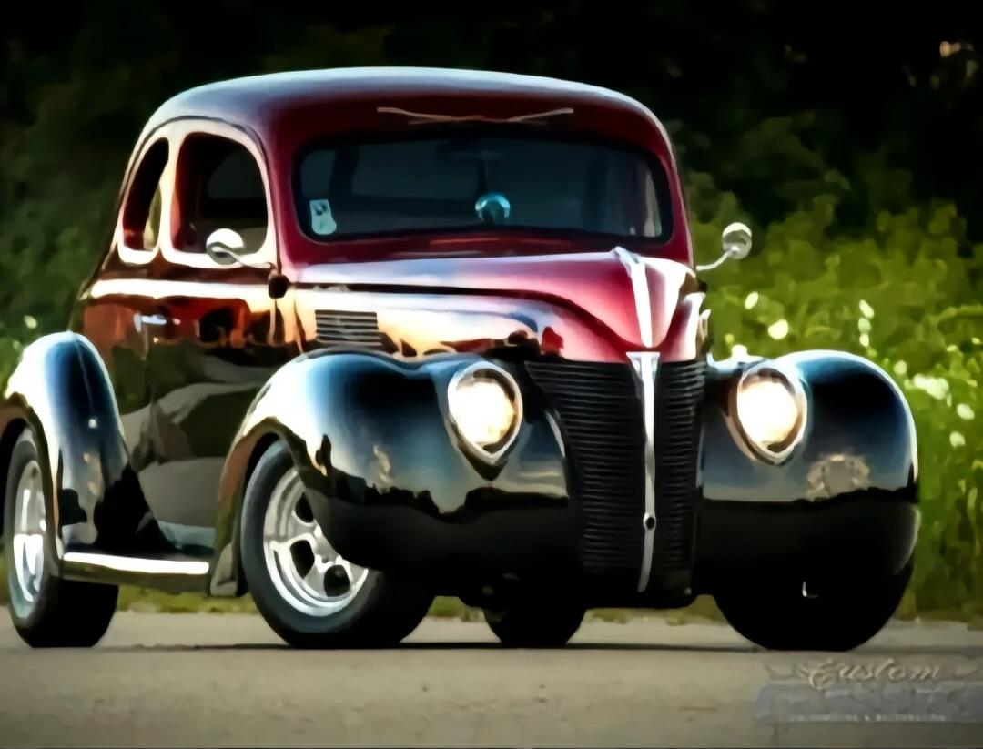 A vintage black and red classic car photographed on a road.