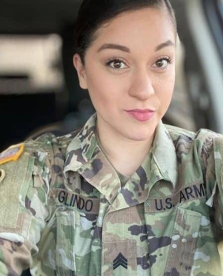 A woman in a U.S. Army uniform with the name 'GLINDO' and 'U.S. ARMY' visible, along with Staff Sergeant rank insignia.