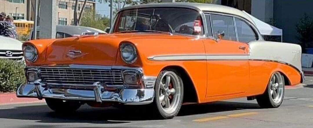 A vintage orange and white classic car parked on the street.