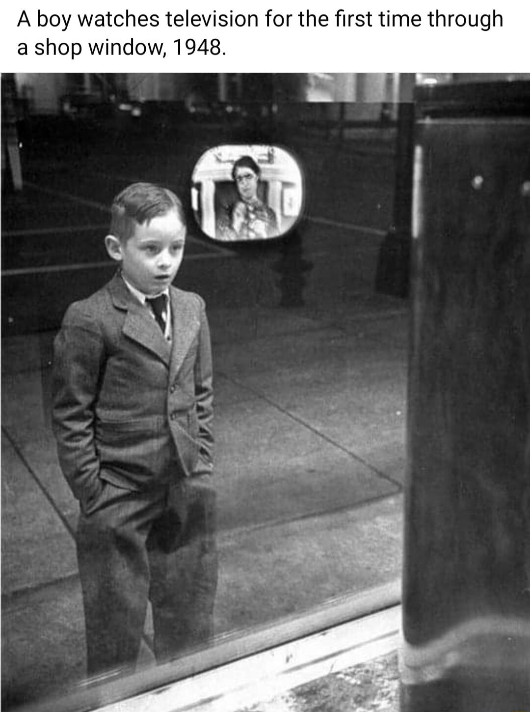 A boy watches television for the first time through a shop window 1948