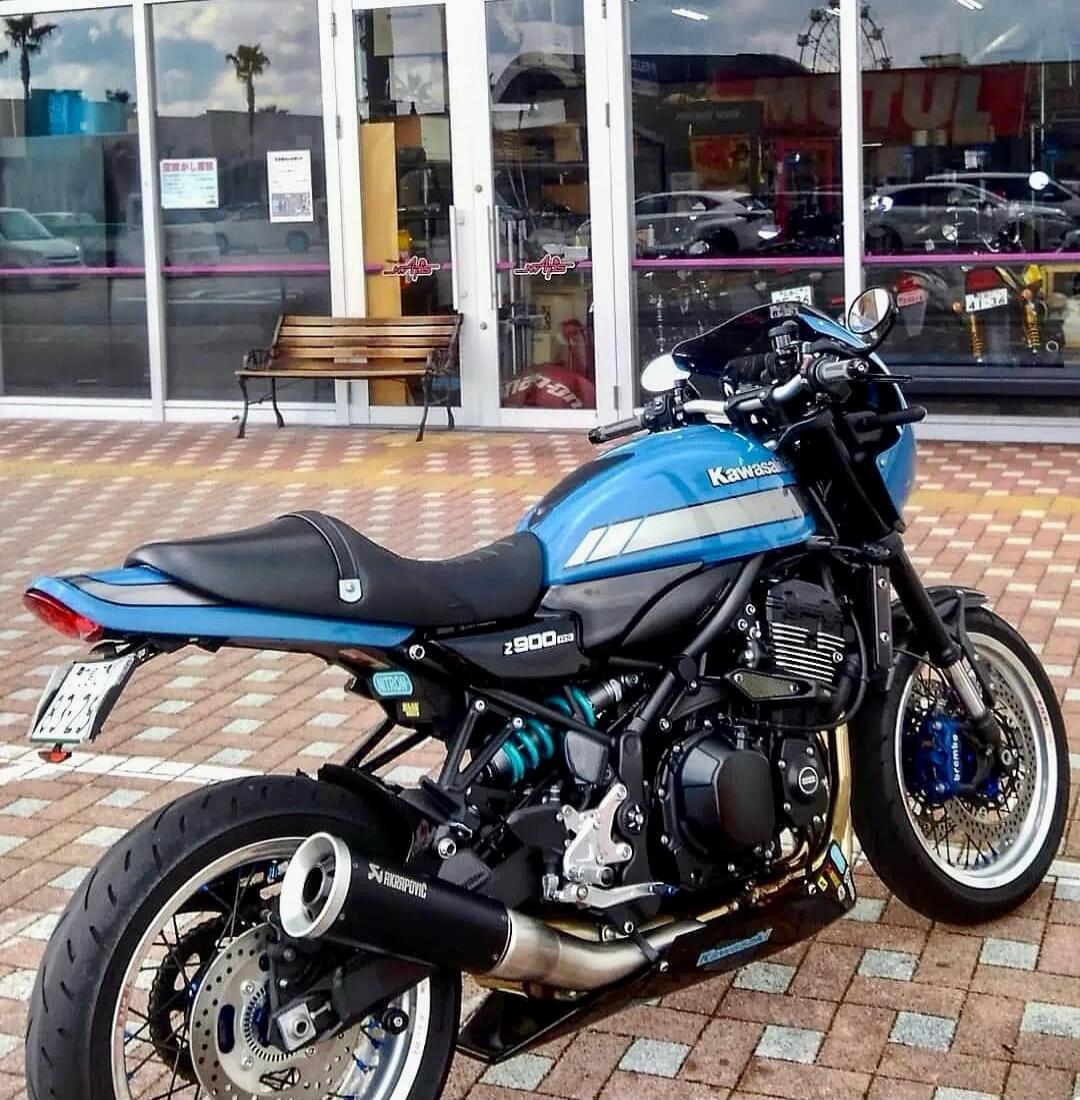 Kawasaki Z900RS motorcycle with Akrapovic exhaust, Nitron suspension, and Brembo brakes. Text on building: 'Holiday notice'.