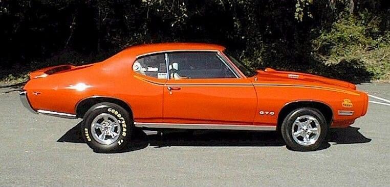 Orange vintage muscle car (classic car) parked on a road.