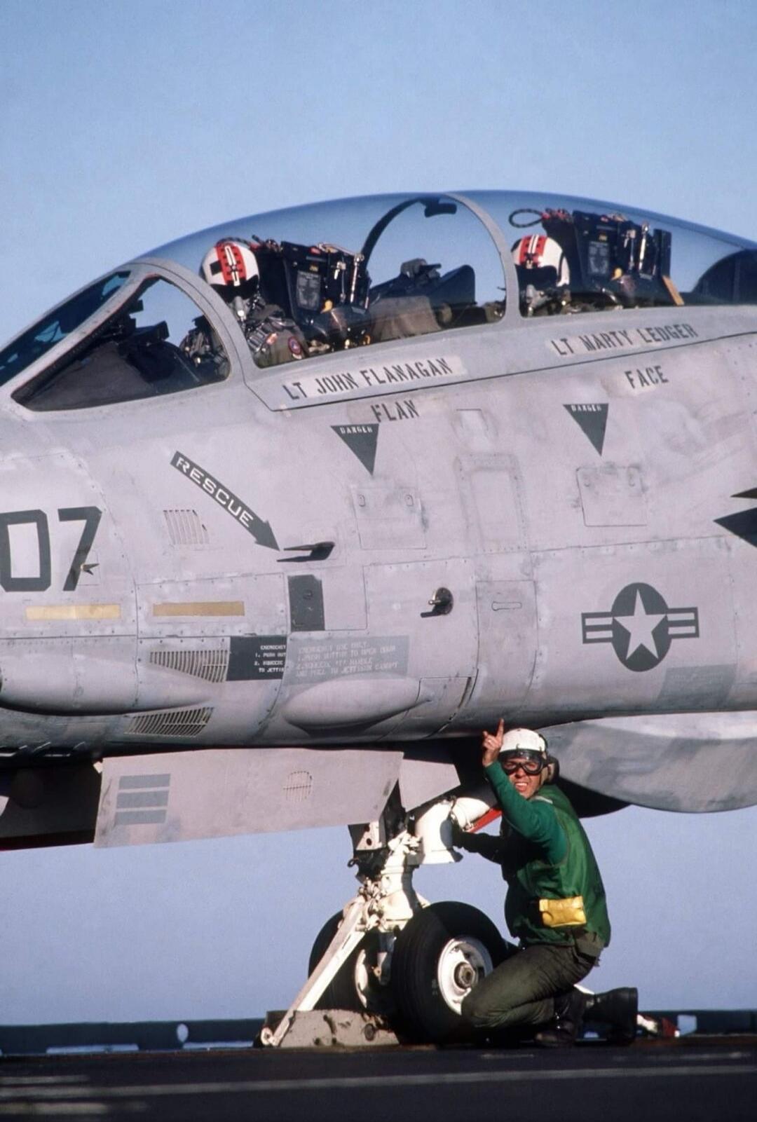 RESCUE 07 — LT JOHN FLAMGAN — LT MARY CHESE (illegible) on cockpit side; ground crew in green uniform giving thumbs up; fighter jet with US star insignia and rescue markings.