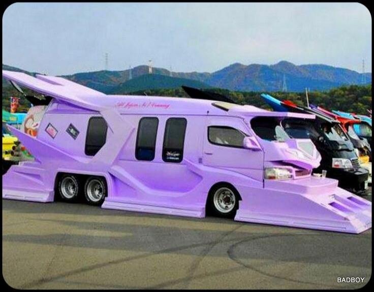 BADBOY. A heavily customized, futuristic-looking purple van with extreme body modifications, resembling a lowrider or an anime vehicle, parked at what appears to be a car show or meeting.